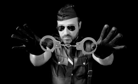 MAn showing the handcuffs in first plane, wearing leather, and sunglasses.